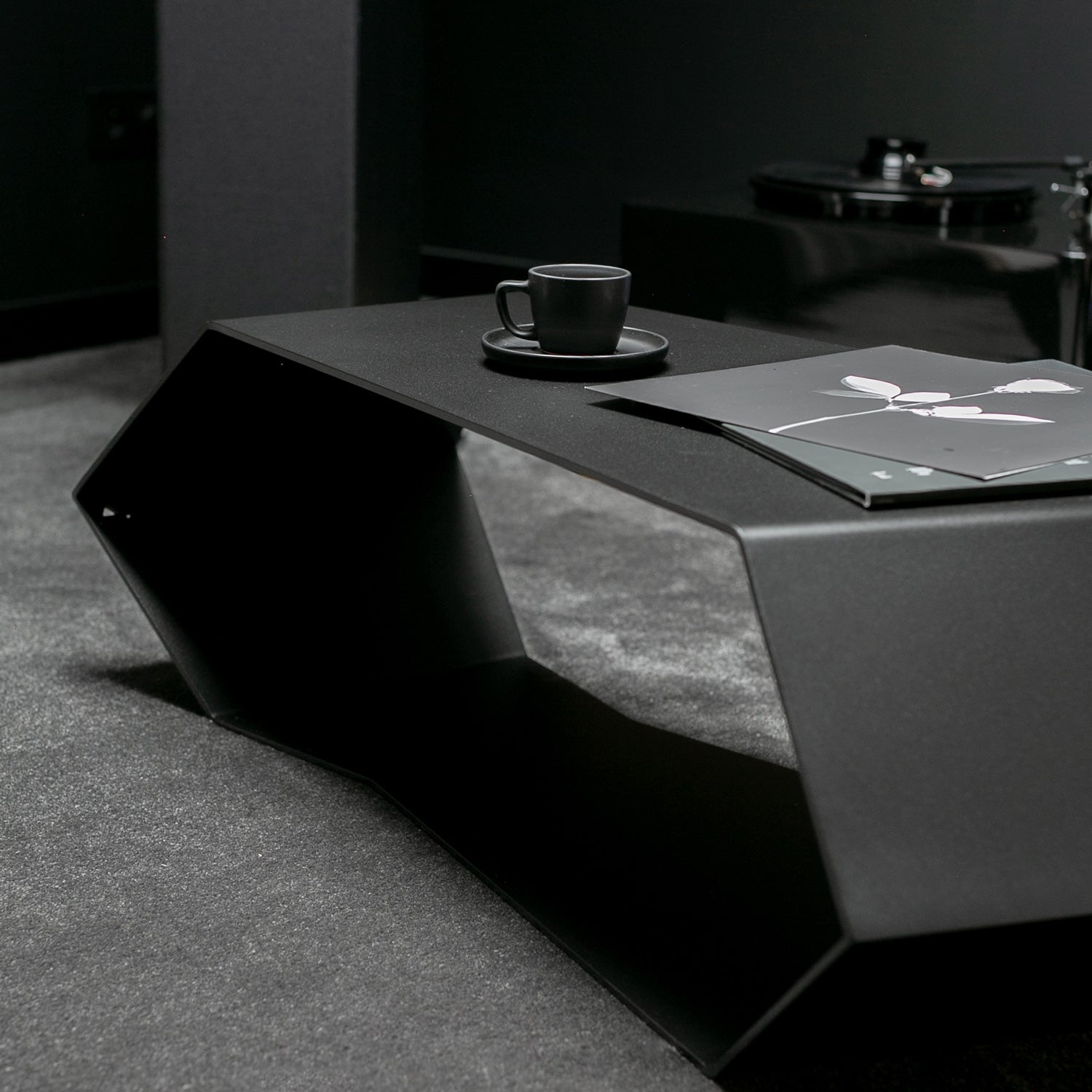 black contemporary coffee table with a cup and saucer on a dark surface