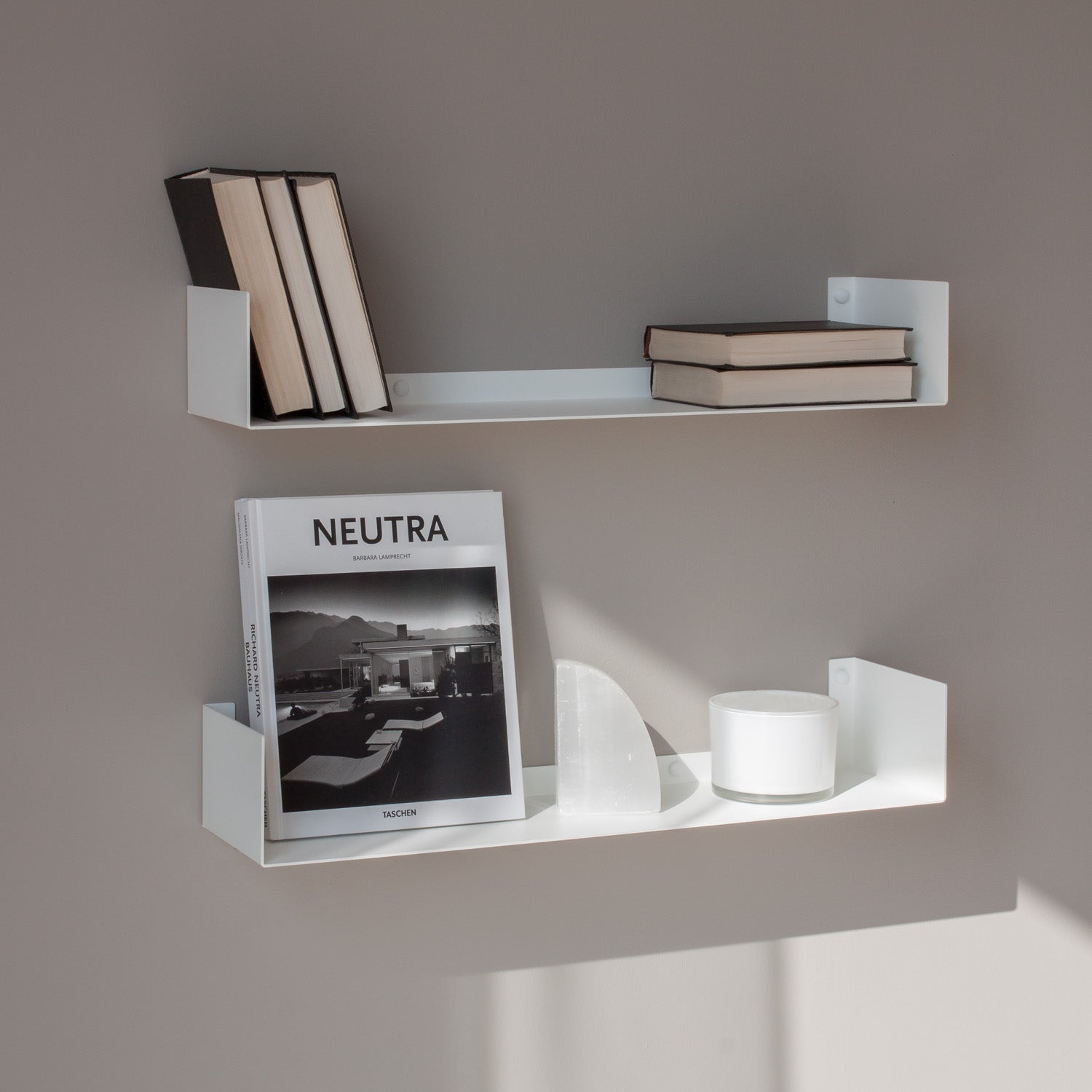 White wall shelves with books and a magazine on a gray wall