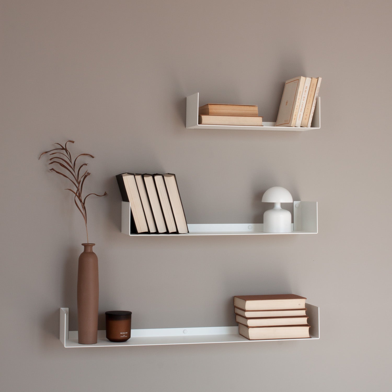 White shelves with books and decorative items against a beige wall