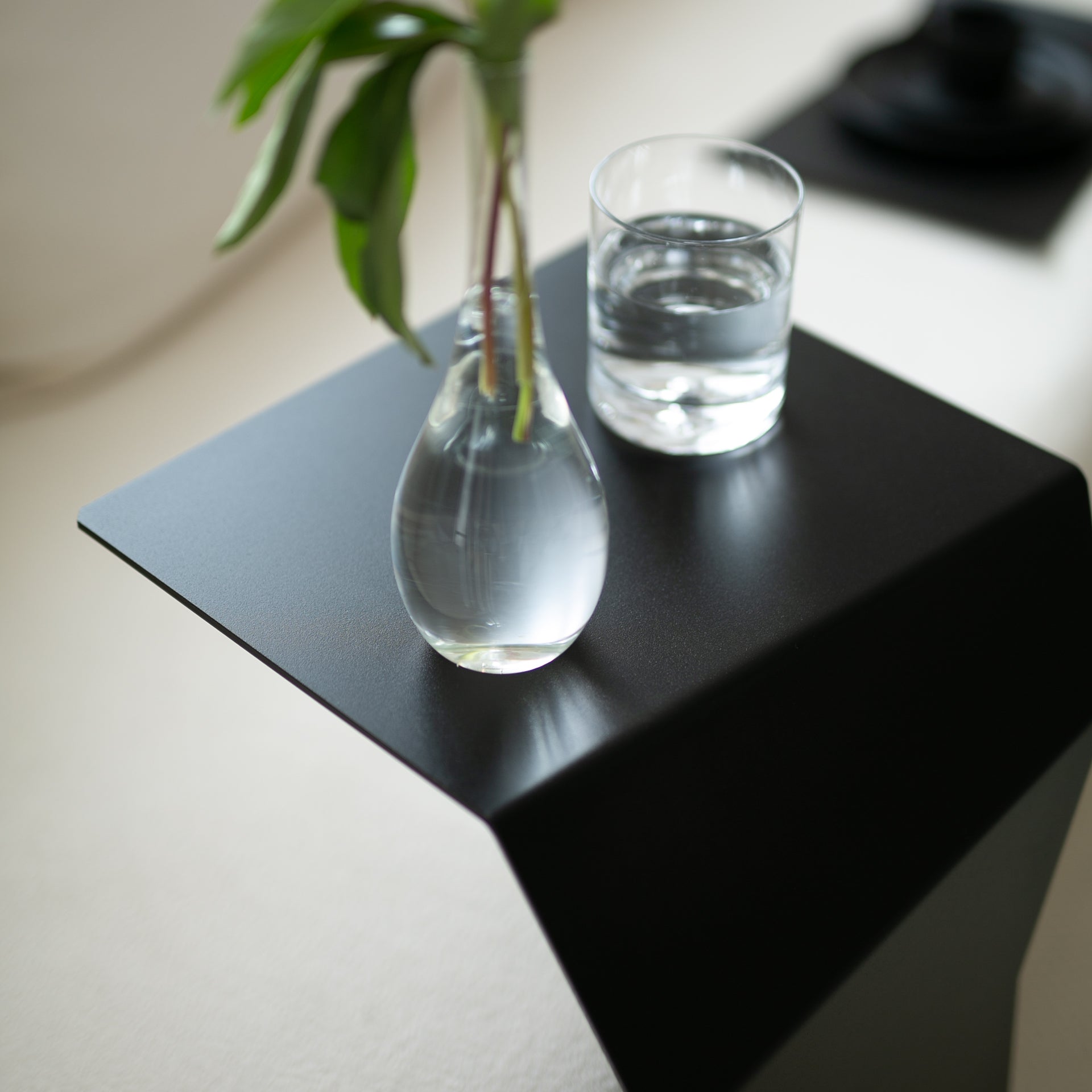 black designer end table with glass and flower