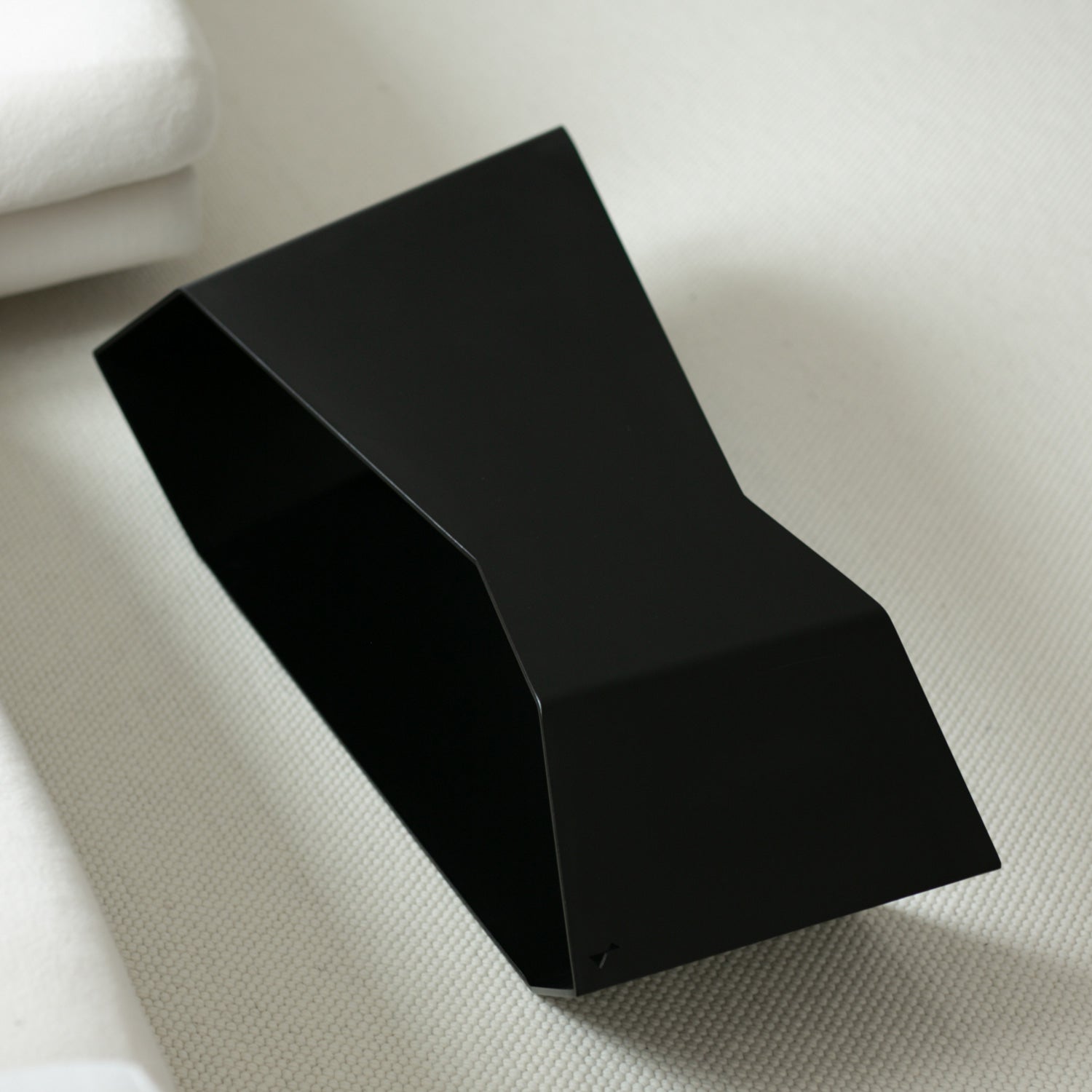 Black coffee table in upside-down configuration placed on cream carpet