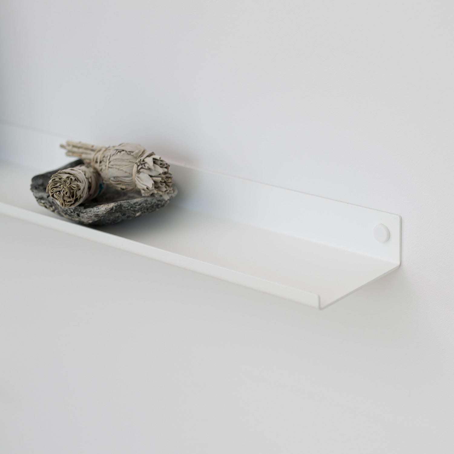 White display wall shelf with palo santo on white wall