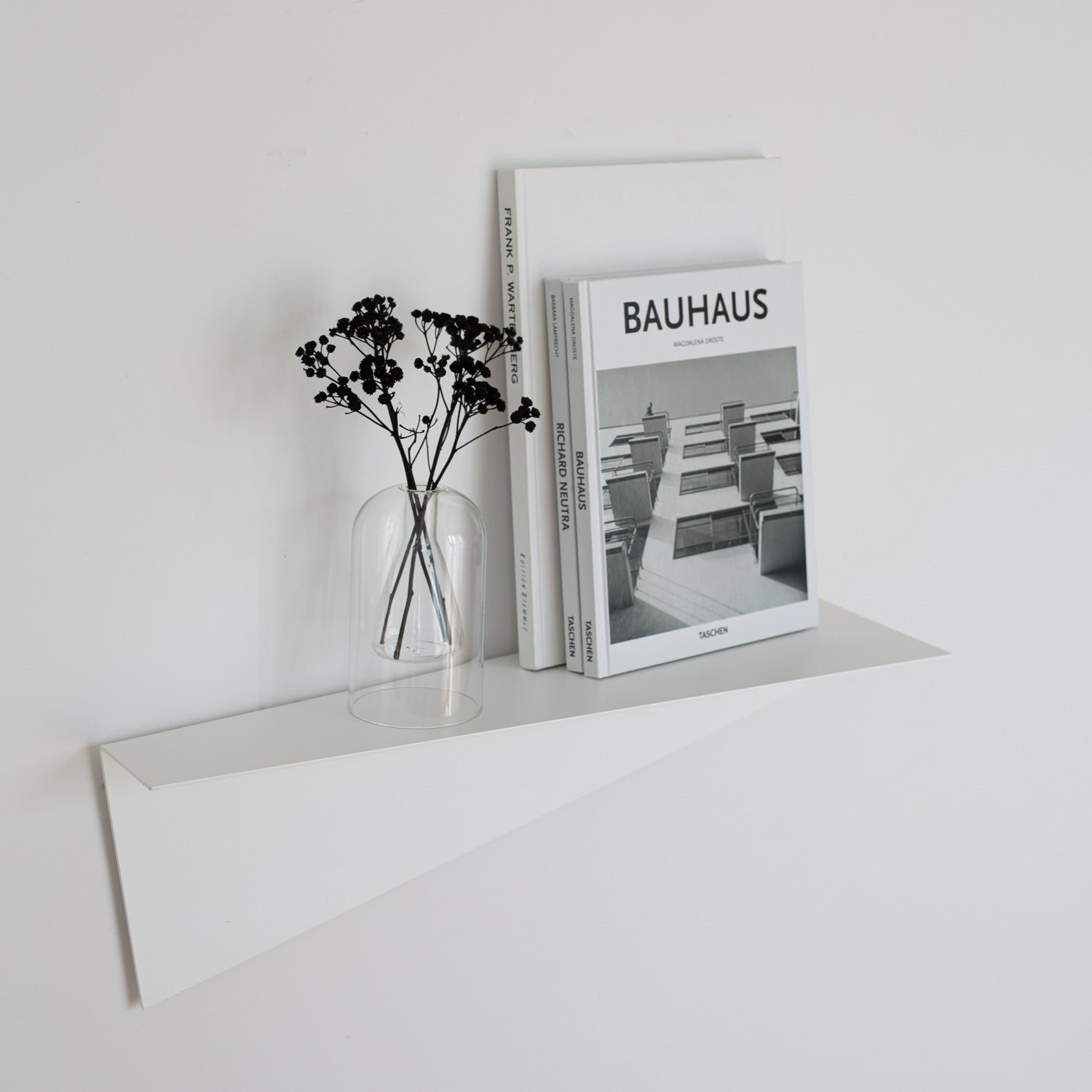 white geometric wall shelf with books and flowers on white wall