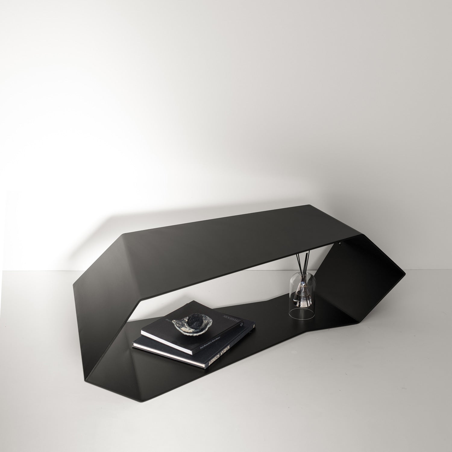 Black designer metal coffee table with unique cutout on white floor