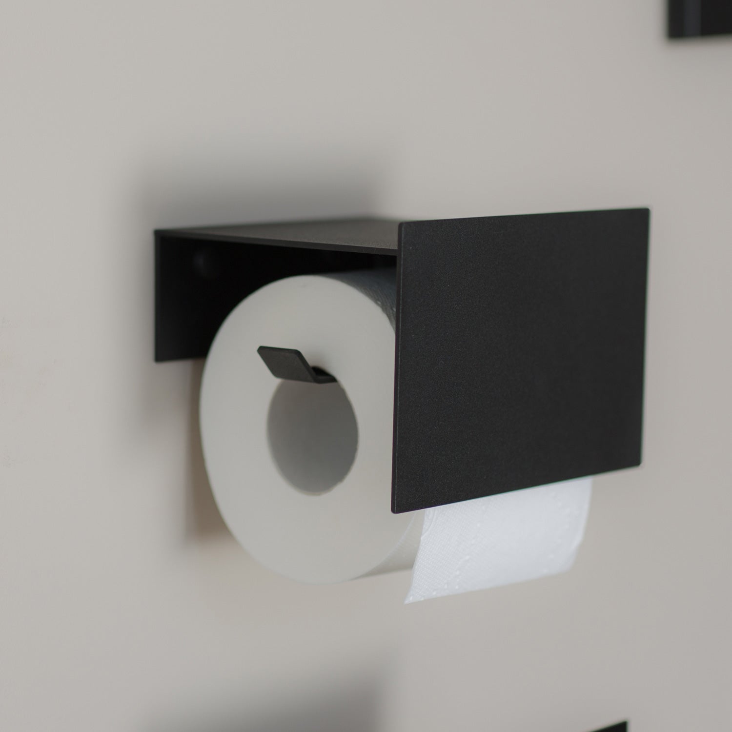 black toilet paper holder on beige tiles