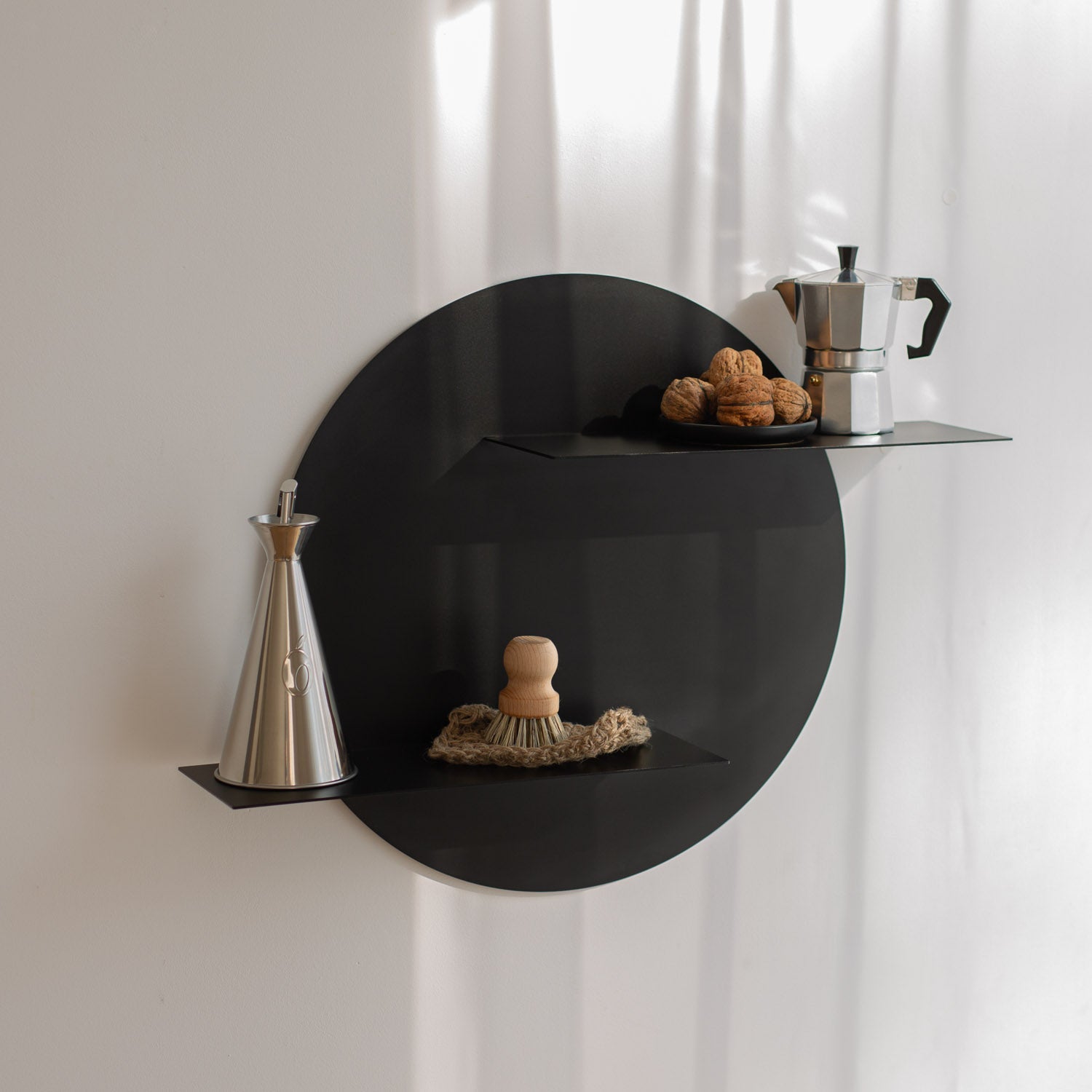 Black circular wall shelf with decorative items against a white curtain background