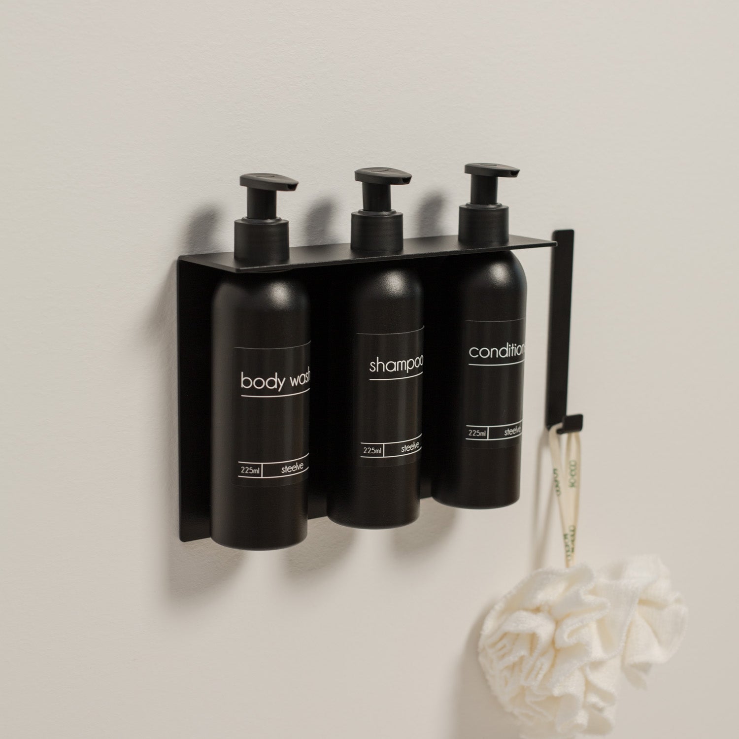 Set of three black pump bottle dispensers mounted without drilling under shower