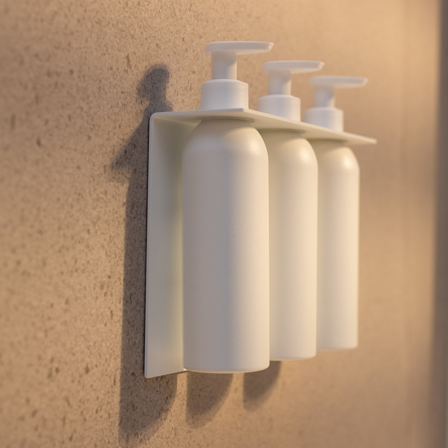 Set of three no-drill soap bottles with pumps on a beige wall