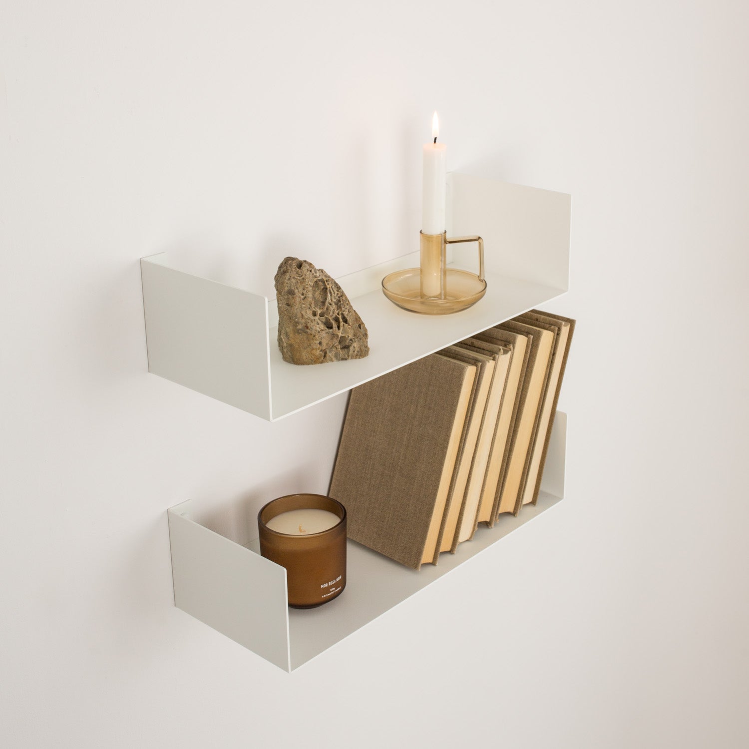White small bookshelf with books, candles, and decoration on a light gray background