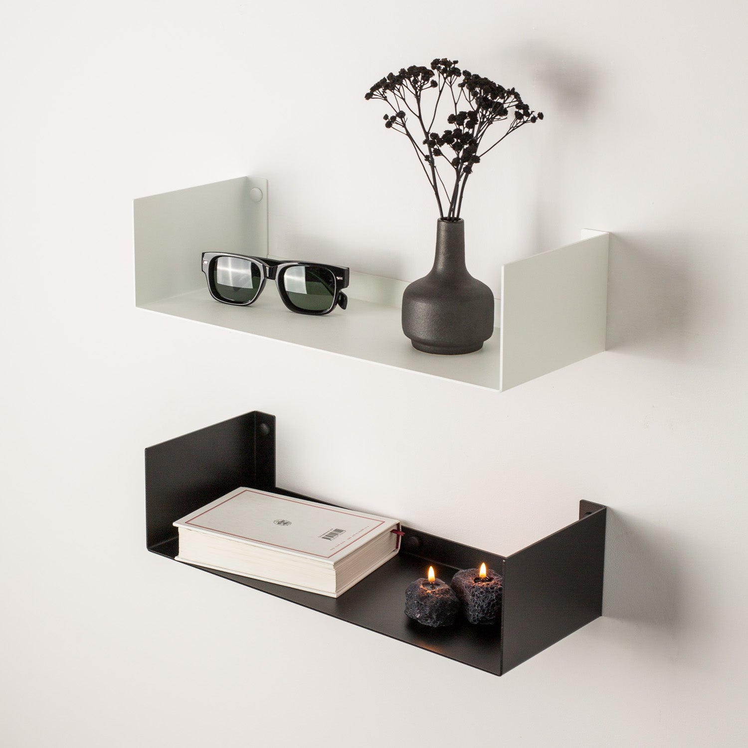 White and black wall shelves with a vase, glasses, and books on a white background