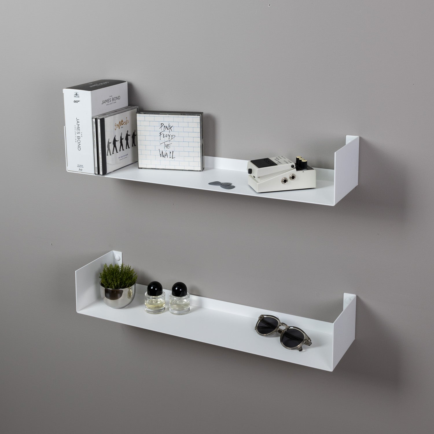 Two white wall shelves against a gray wall with decorative items on them.