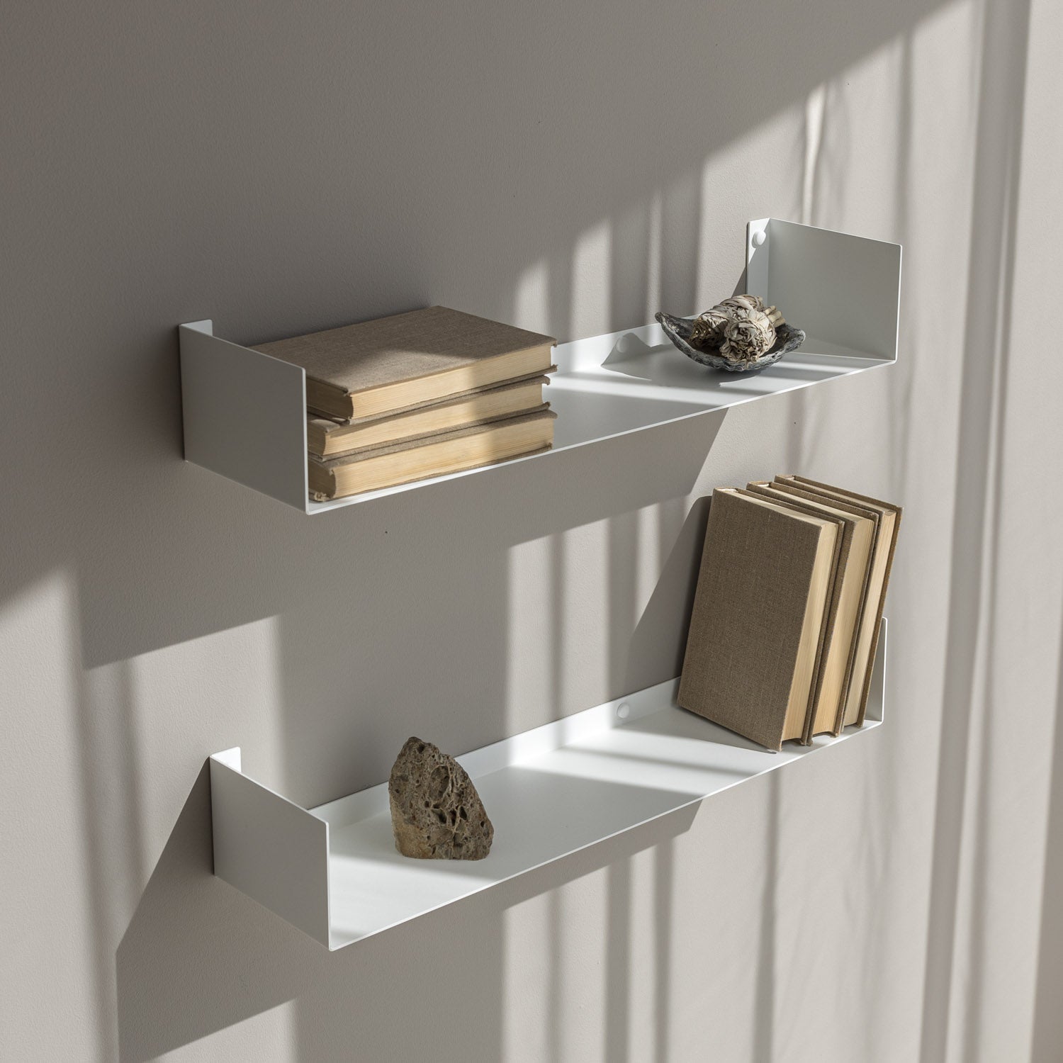 White wall shelves with books and decorative items against a neutral wall.