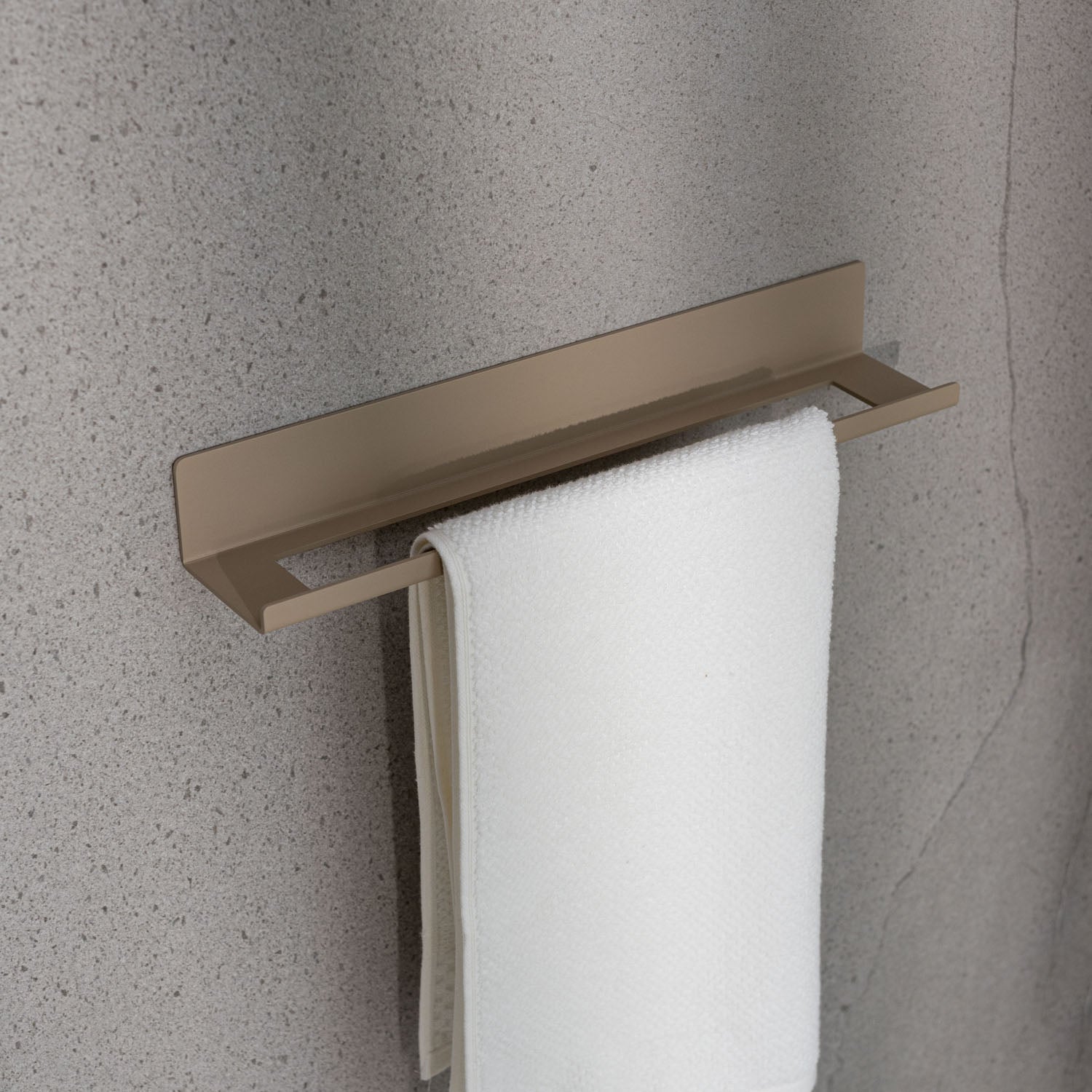 Beige small towel rack with a white towel on a gray wall