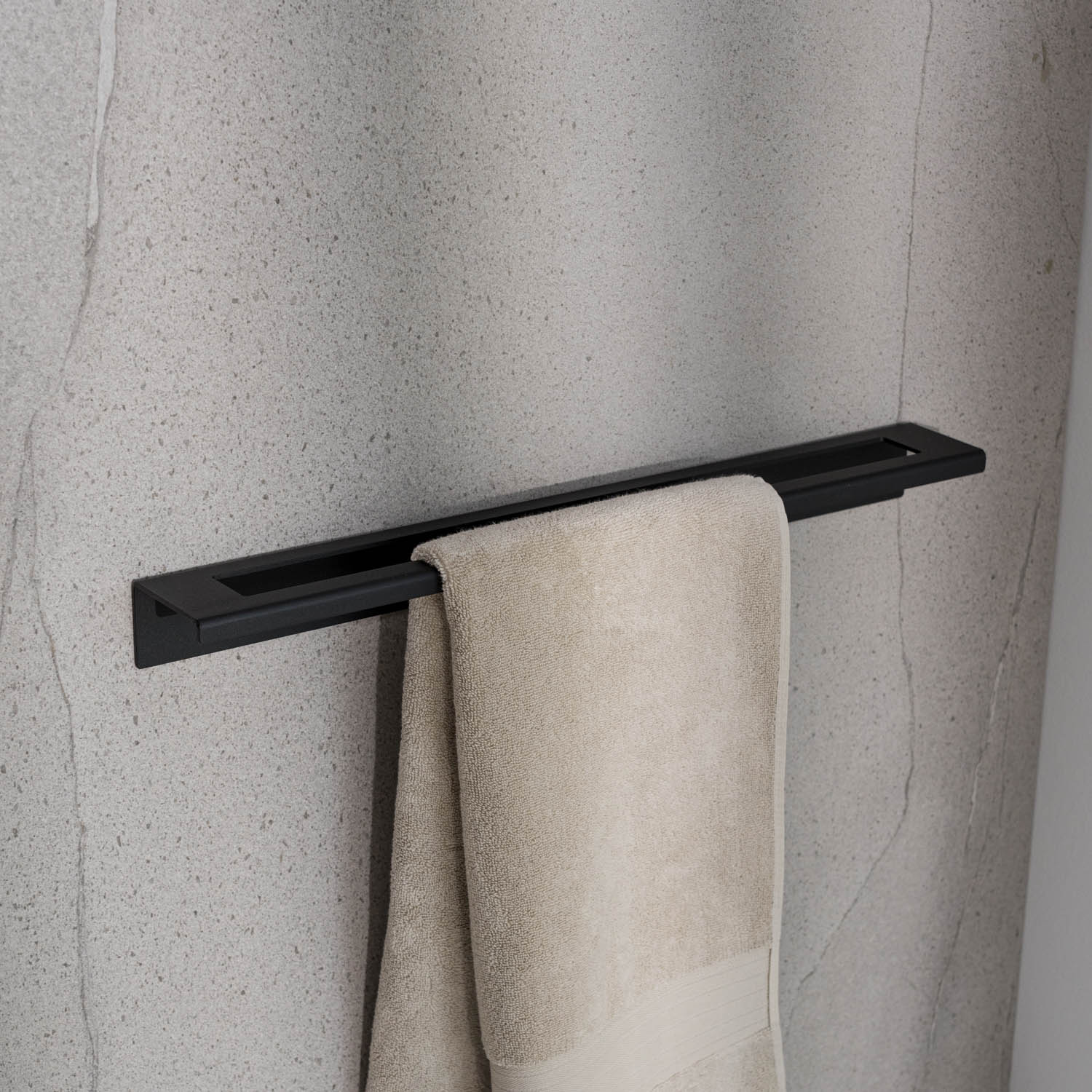 Black large towel rack with a beige towel on a textured gray wall