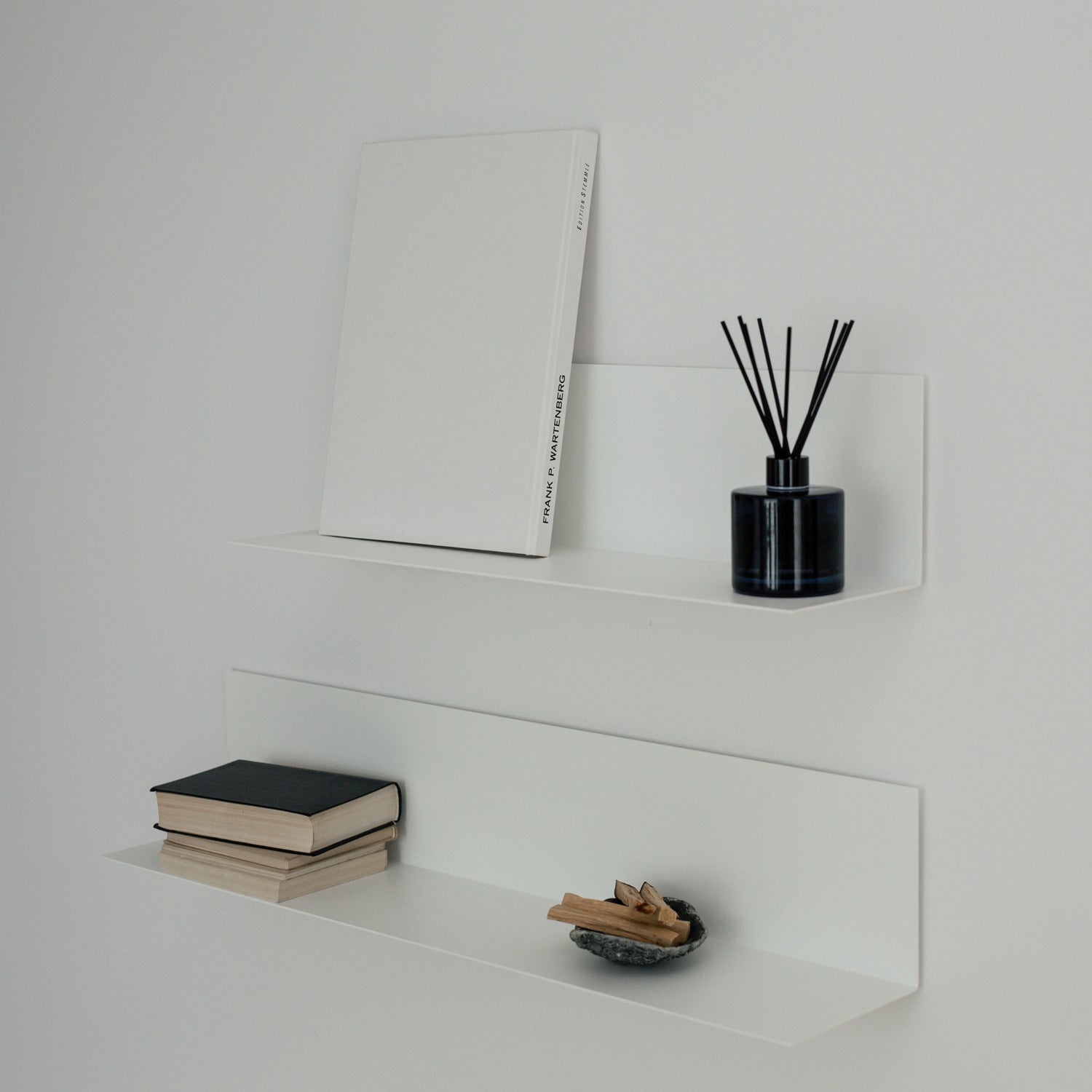 Two white modern shelves with wall decor on white wall