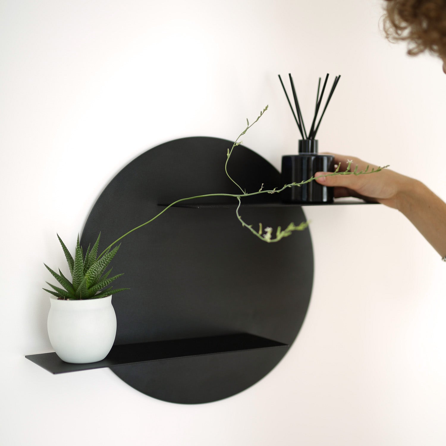 black modern round wall shelf with decoration on white wall 
