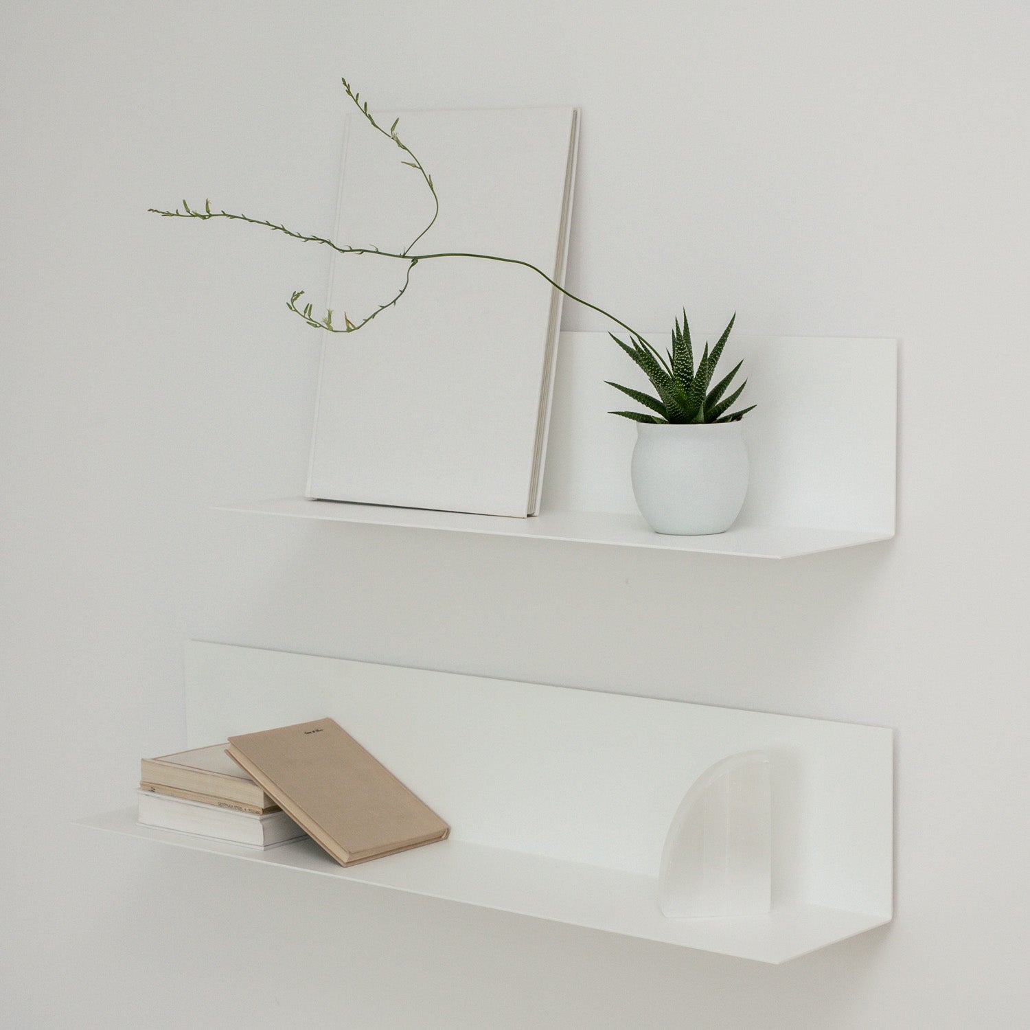 two white bookshelves with decoration on white wall