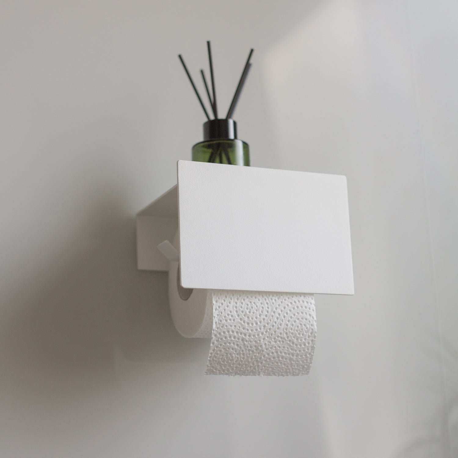 white toilet paper holder tape mounted to grey tiles