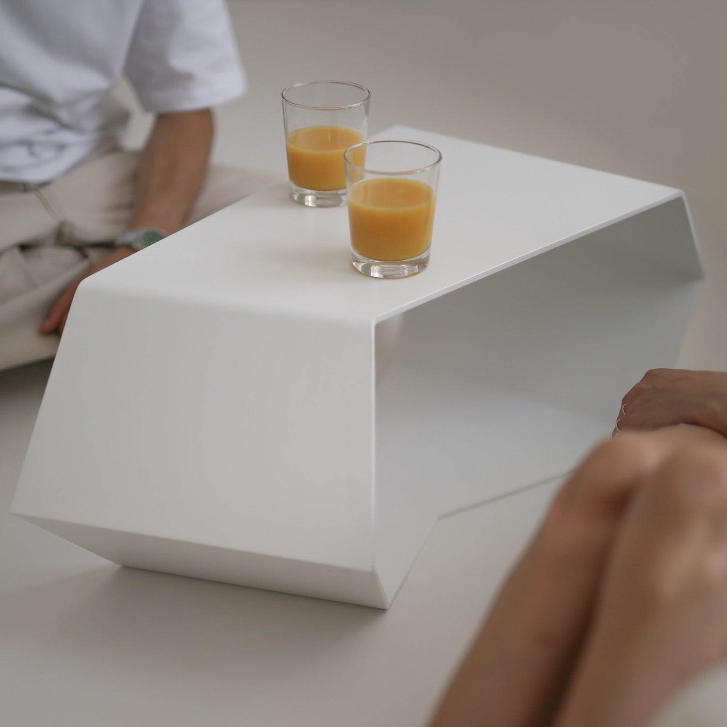 Modern aluminium white coffee table with two glasses of orange juice on a neutral background