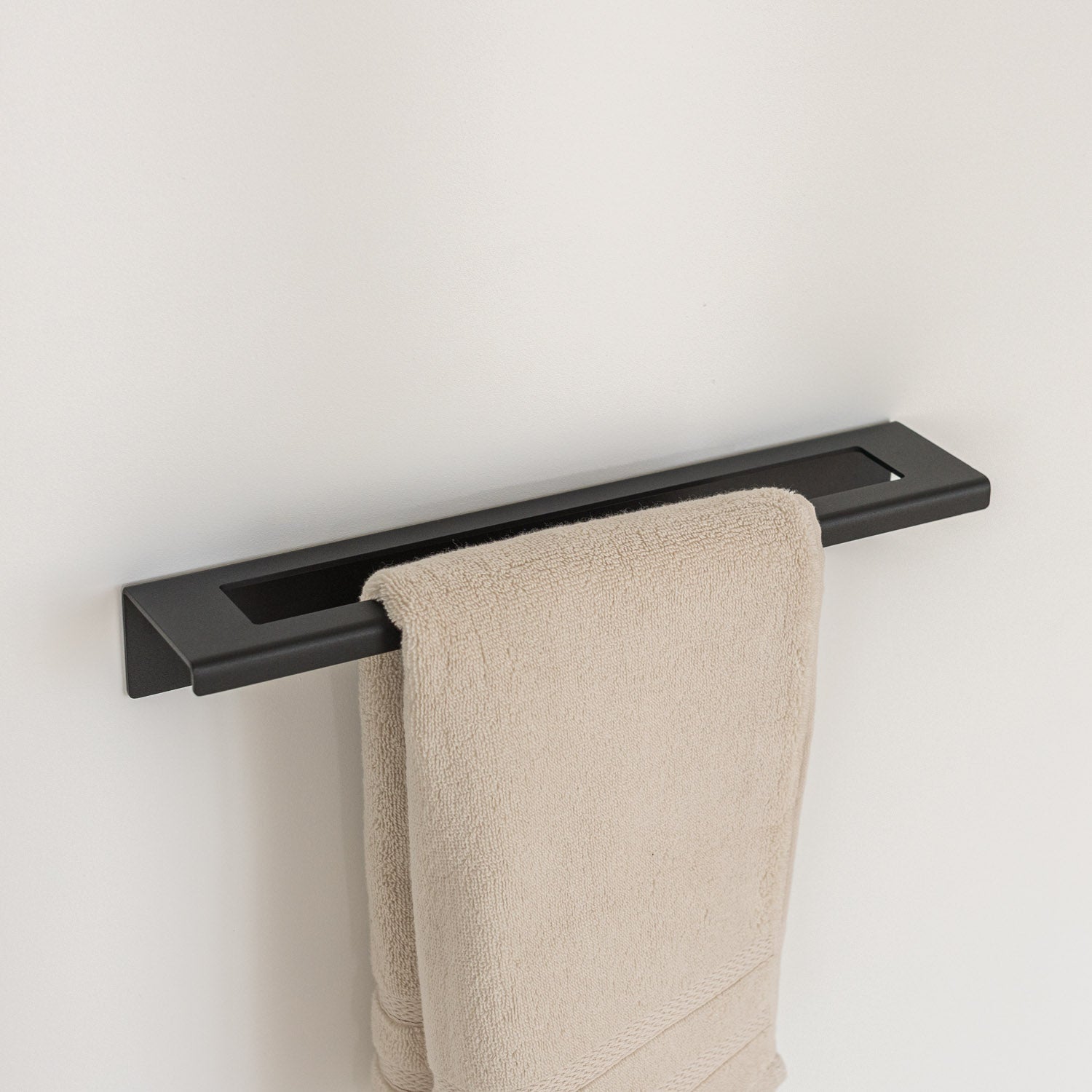 Modern Black towel rack with a beige towel on a white wall