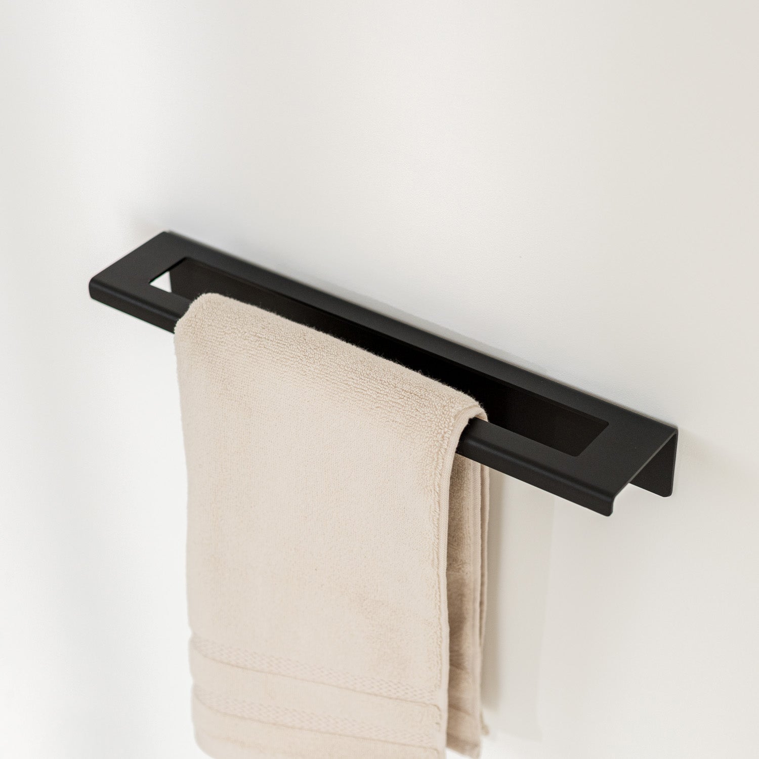 Black towel rack with a beige towel on a white background