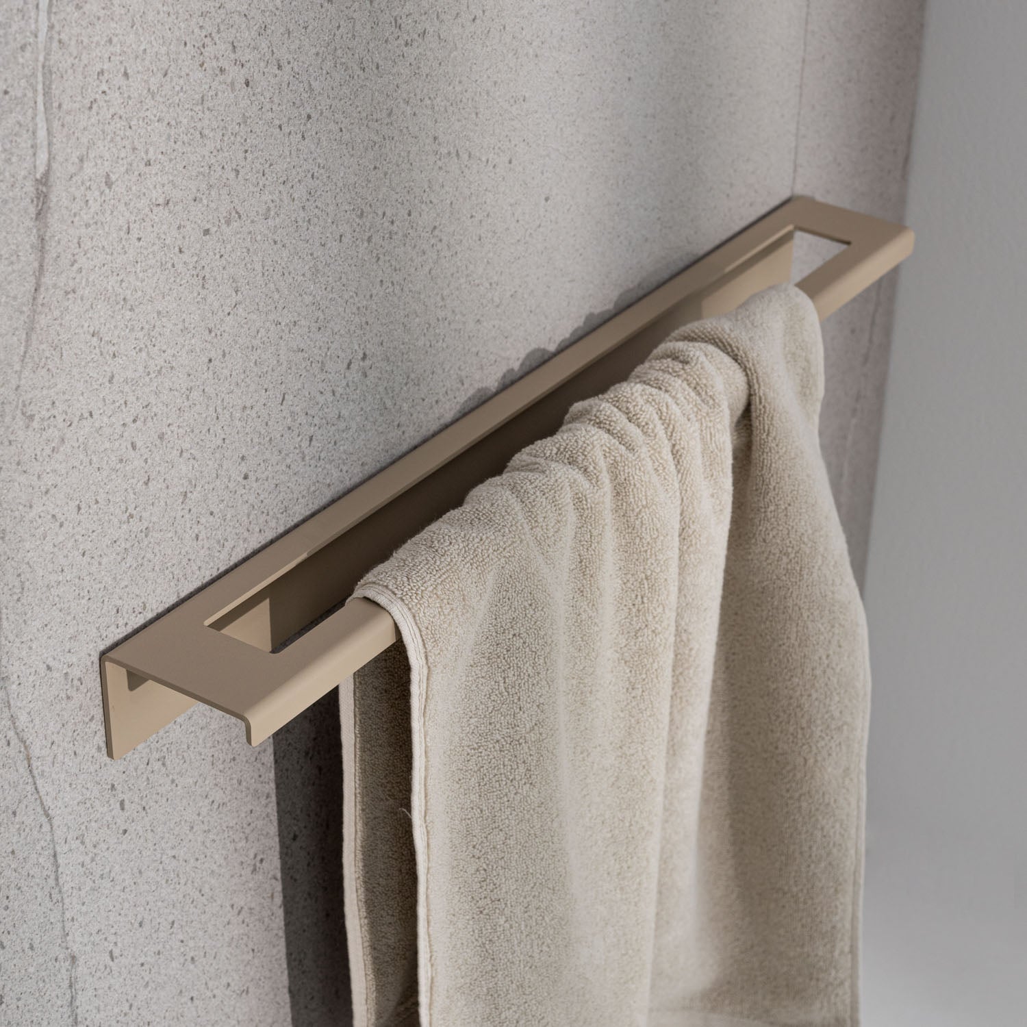 Scandi beige towel rack with a beige towel on a textured gray wall