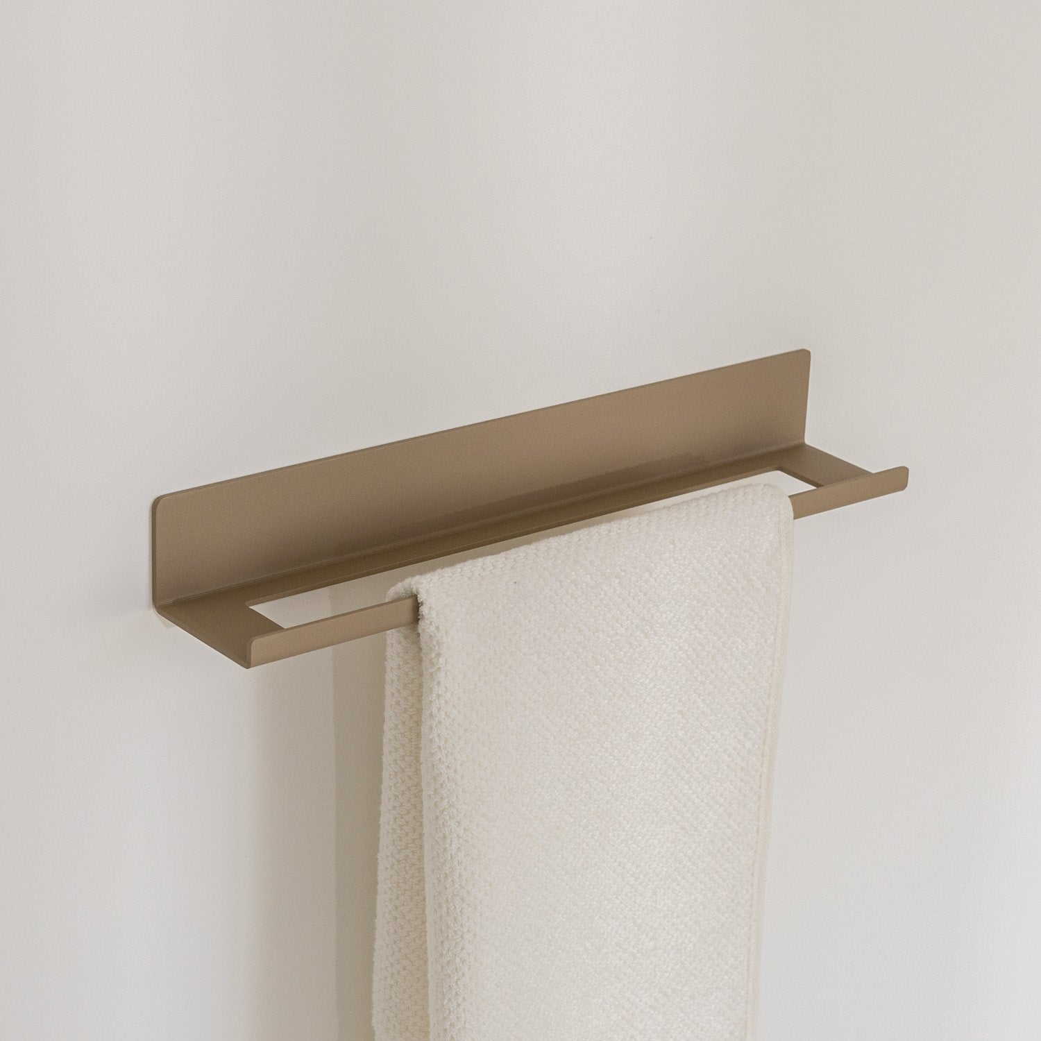 Scandi beige no-drill towel rack with a white towel on a light gray background