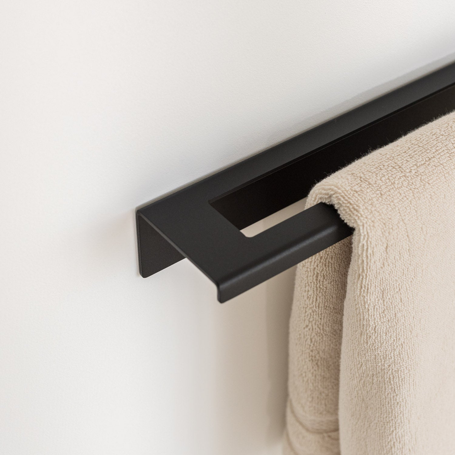Black no-drill towel rack with a beige towel in modern bathroom